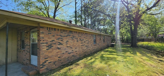 view of home's exterior with a lawn, central AC unit, and brick siding