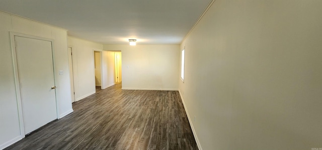 empty room featuring baseboards, dark wood-style floors, and ornamental molding