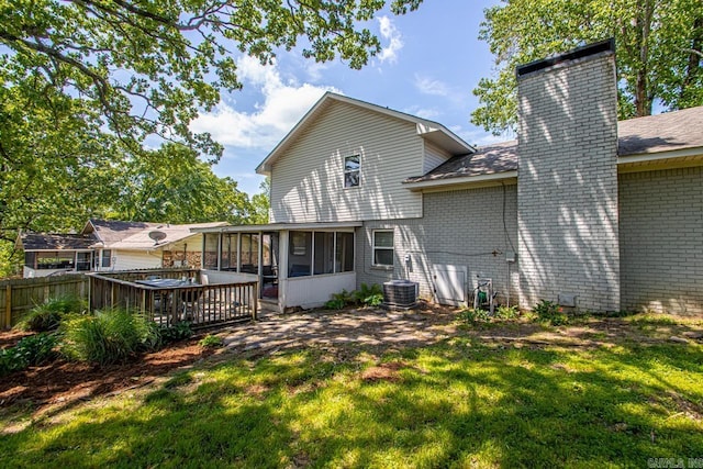 rear view of property with fence, a chimney, a sunroom, brick siding, and a yard