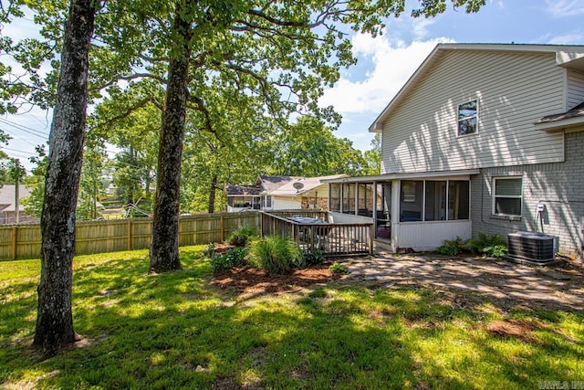 exterior space with fence, a sunroom, a deck, cooling unit, and a yard