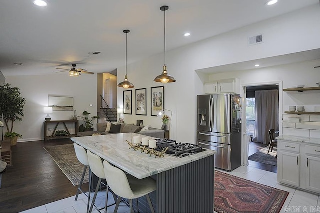 kitchen featuring open shelves, stainless steel refrigerator with ice dispenser, white cabinetry, light stone counters, and a ceiling fan