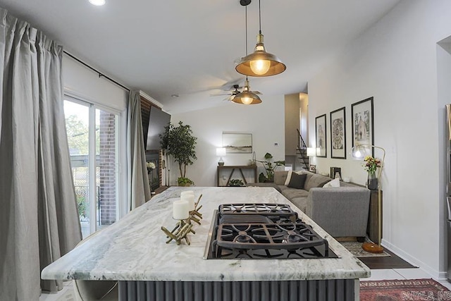 kitchen featuring a ceiling fan, hanging light fixtures, light stone counters, baseboards, and open floor plan
