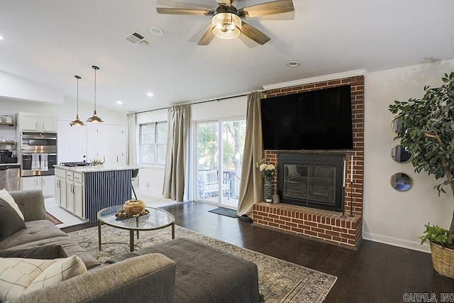 living room with ceiling fan, a fireplace, baseboards, visible vents, and dark wood-style floors