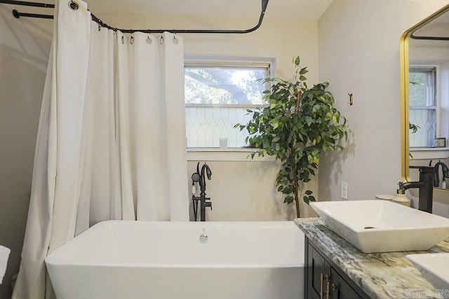 full bath featuring double vanity, a sink, and a freestanding tub