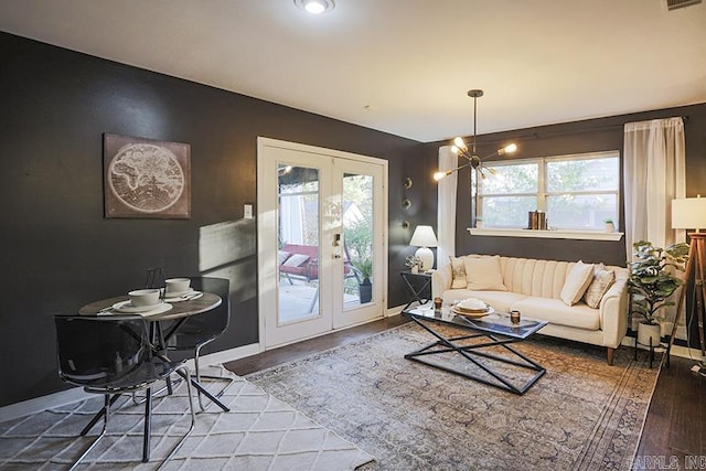 living room featuring visible vents, wood finished floors, baseboards, a chandelier, and french doors