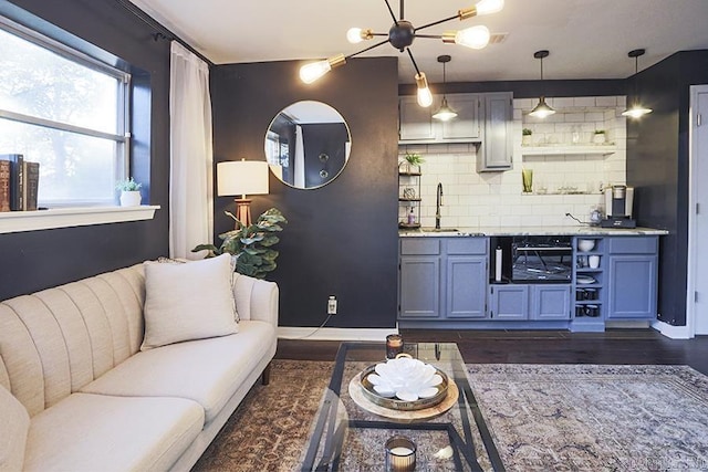 living room featuring baseboards, dark wood-style flooring, and a notable chandelier