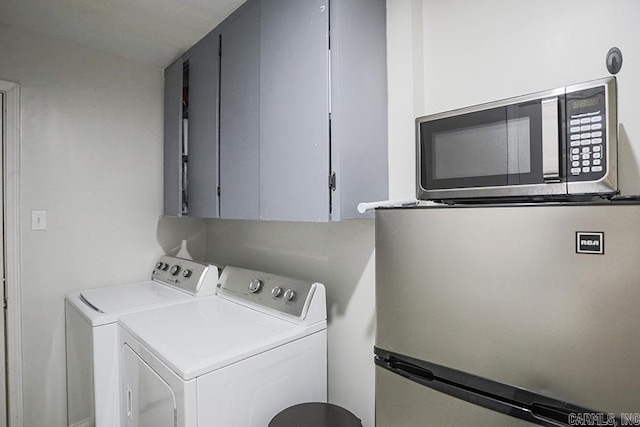 clothes washing area featuring separate washer and dryer and cabinet space