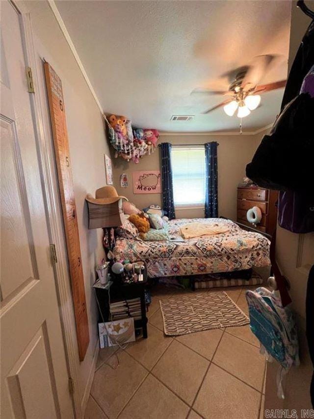 tiled bedroom featuring crown molding, a ceiling fan, and visible vents