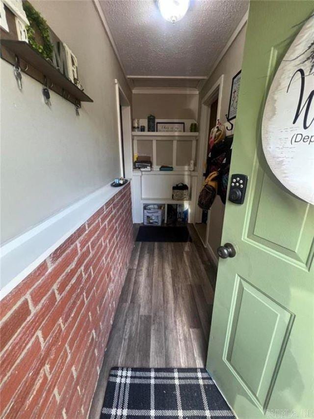 corridor featuring brick wall, a textured ceiling, and wood finished floors
