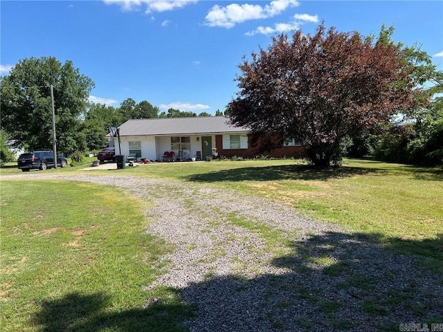 view of front of home with a front lawn, driveway, and metal roof
