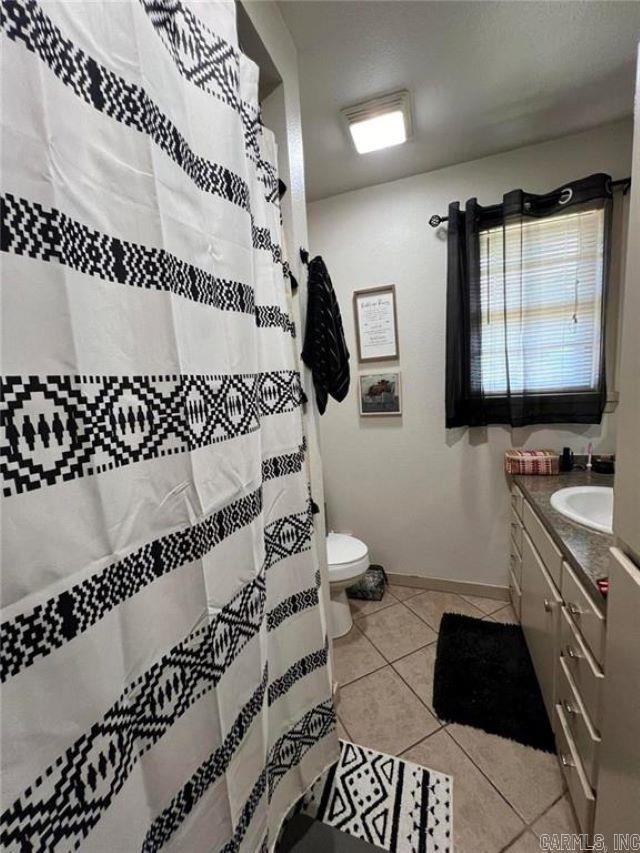 bathroom with vanity, tile patterned floors, toilet, and curtained shower