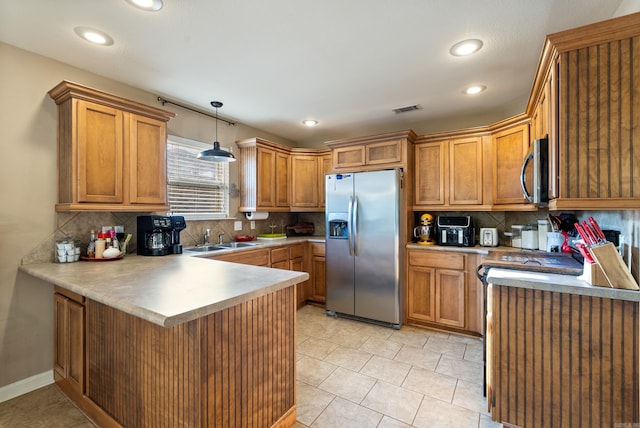 kitchen with backsplash, visible vents, a sink, a peninsula, and stainless steel appliances