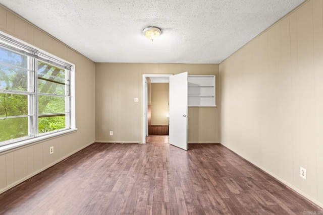 unfurnished bedroom with a closet, baseboards, a textured ceiling, and wood finished floors