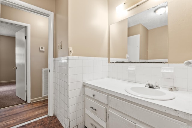 bathroom with vanity, a textured ceiling, wood finished floors, and visible vents