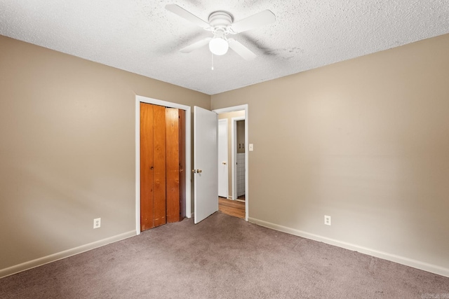 unfurnished bedroom with ceiling fan, a textured ceiling, baseboards, a closet, and carpet flooring