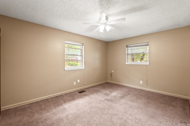carpeted empty room with baseboards, a ceiling fan, a textured ceiling, and visible vents