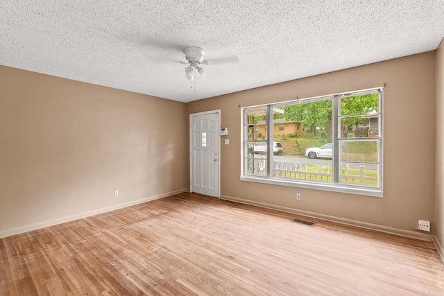 empty room with visible vents, a ceiling fan, light wood-style floors, and baseboards