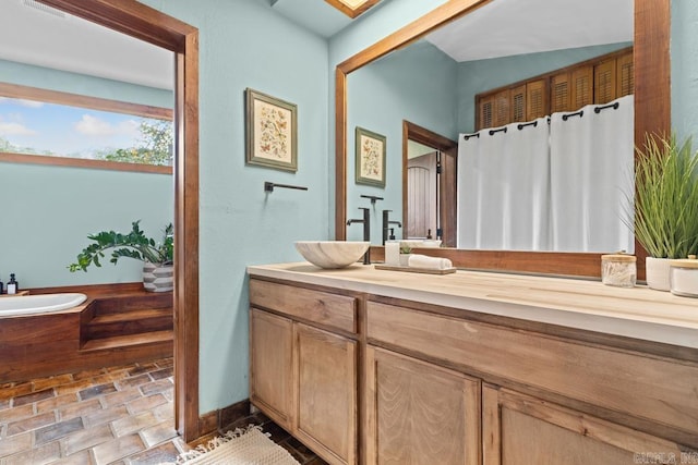 bathroom with stone finish floor, vanity, and a bath