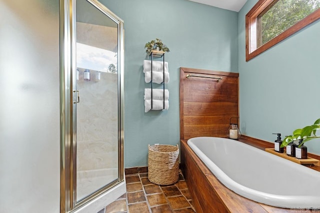 bathroom featuring stone finish floor, a bath, and a stall shower