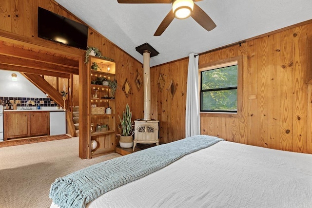 carpeted bedroom with wooden walls, vaulted ceiling, and a wood stove