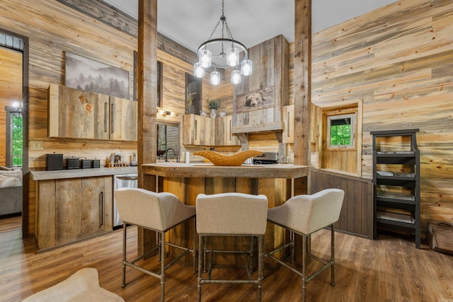 kitchen with stainless steel dishwasher, a peninsula, a notable chandelier, wooden walls, and a high ceiling