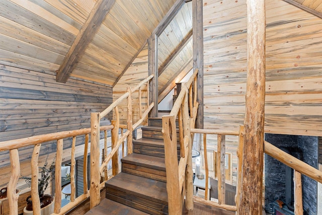 stairway with wood walls, lofted ceiling with beams, wood finished floors, and wooden ceiling