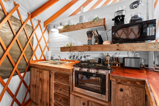 kitchen with black microwave, open shelves, wood finished floors, a sink, and vaulted ceiling with beams