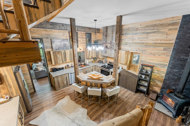 dining area featuring wood walls, wood finished floors, a wood stove, and an inviting chandelier