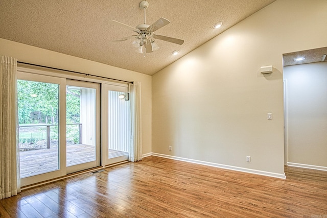 spare room with ceiling fan, a textured ceiling, baseboards, wood finished floors, and vaulted ceiling