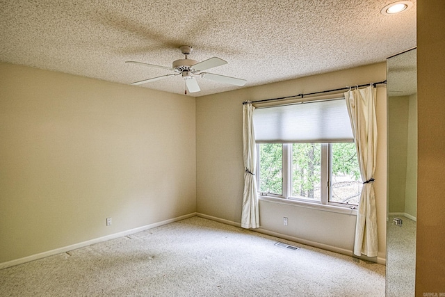 carpeted spare room featuring baseboards, a ceiling fan, and visible vents
