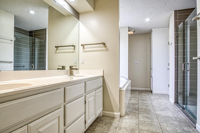 bathroom featuring double vanity, a textured ceiling, a shower stall, and a sink