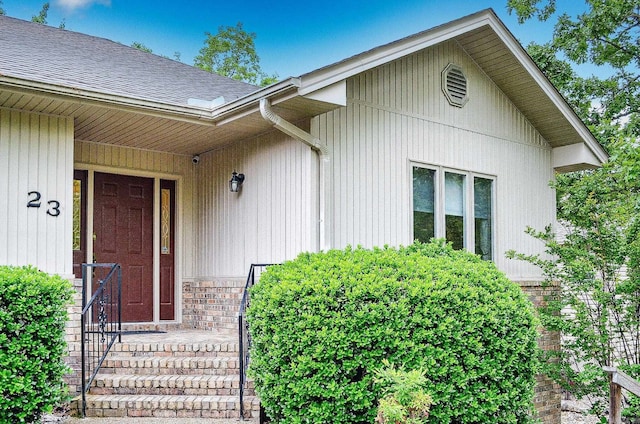view of exterior entry with roof with shingles