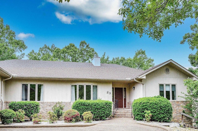 ranch-style home featuring brick siding and roof with shingles