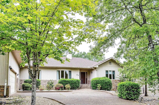ranch-style home featuring brick siding, roof with shingles, and a chimney