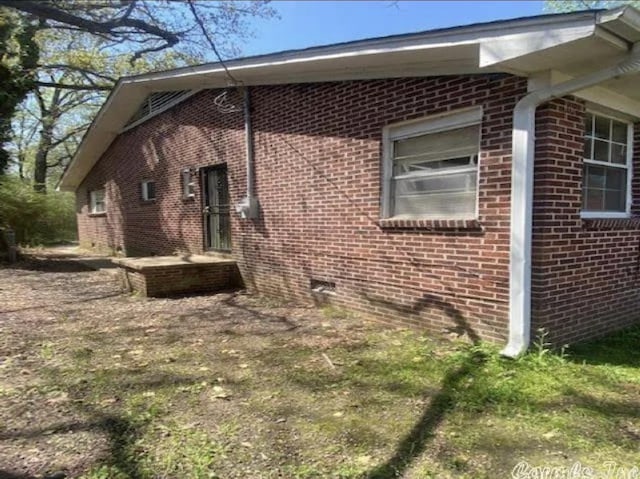view of property exterior with brick siding and crawl space
