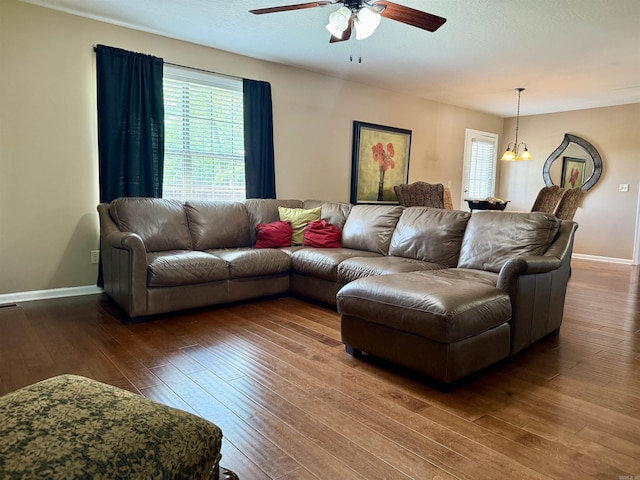 living area featuring baseboards, ceiling fan with notable chandelier, visible vents, and hardwood / wood-style flooring