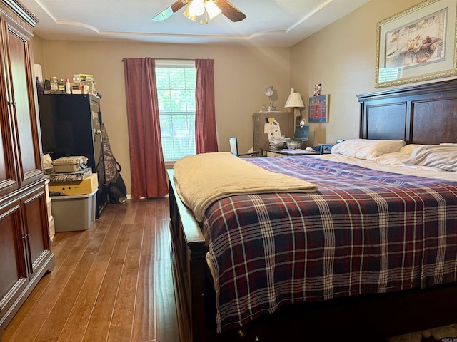 bedroom featuring a raised ceiling, a ceiling fan, and hardwood / wood-style flooring