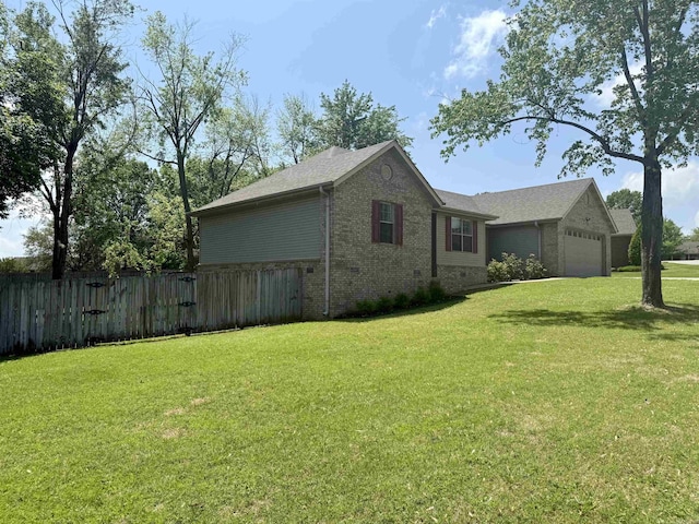 view of side of property featuring fence, an attached garage, a lawn, and brick siding
