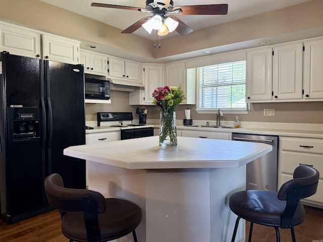 kitchen featuring a sink, a kitchen breakfast bar, black appliances, and ceiling fan