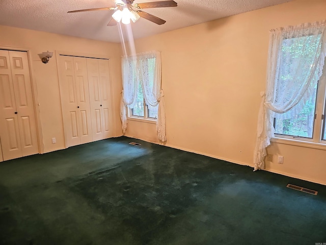 50 Monovar Cir, Hot Springs Village, AR 71909 - unfurnished bedroom with multiple closets, dark colored carpet, multiple windows, baseboards, and a textured ceiling