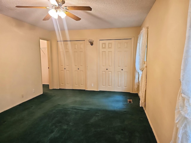 50 Monovar Cir, Hot Springs Village, AR 71909 - unfurnished bedroom with a textured ceiling, two closets, baseboards, dark carpet, and ceiling fan