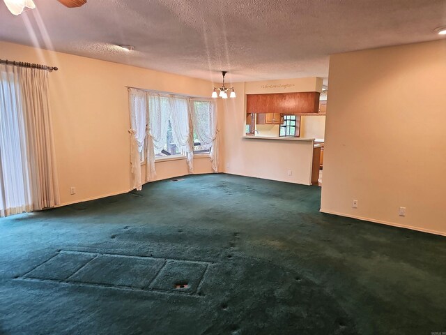 50 Monovar Cir, Hot Springs Village, AR 71909 - unfurnished living room with dark colored carpet, a textured ceiling, a chandelier, baseboards, and a ceiling fan