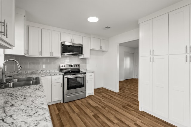 kitchen featuring a sink, dark wood finished floors, stainless steel appliances, decorative backsplash, and visible vents