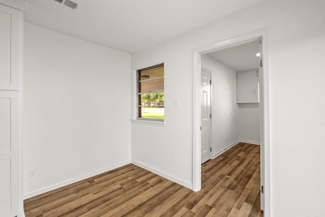 spare room featuring visible vents, baseboards, and wood finished floors