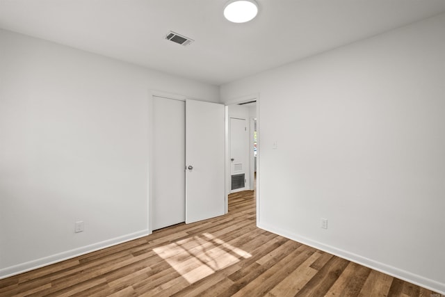 unfurnished bedroom with baseboards, wood finished floors, and visible vents