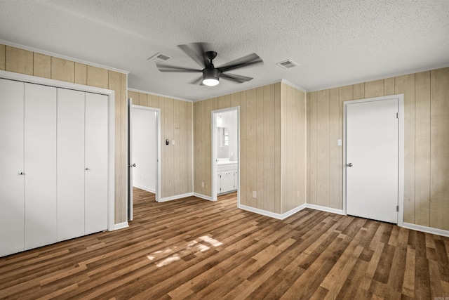 unfurnished bedroom featuring visible vents, baseboards, wood finished floors, and a closet