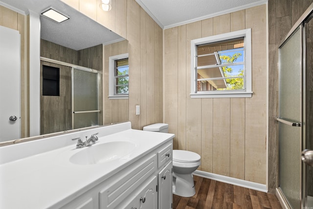 bathroom featuring a stall shower, wood finished floors, toilet, and ornamental molding