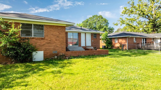 back of house featuring a yard, brick siding, fence, and entry steps