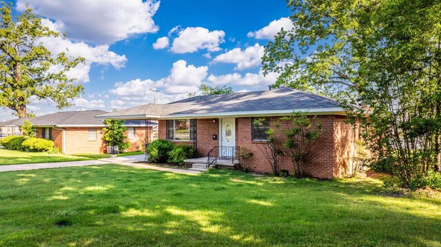 ranch-style home with brick siding, driveway, and a front yard