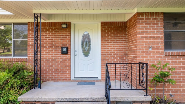 property entrance featuring brick siding and a porch